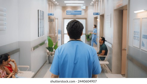 Backview Shot of Young Male Doctor Walking in Hospital Corridor. Indian Professional Medical Specialist Starting his Workday in a Busy Modern Health Clinic - Powered by Shutterstock