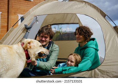 Backyard Camping. Family With A Dog Are Sitting With A Tourist Tent In The Backyard