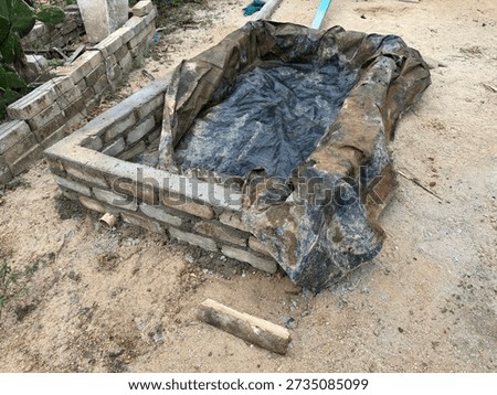 A backyard duck pond structure lined with plastic shows early construction stage for small-scale animal keeping.