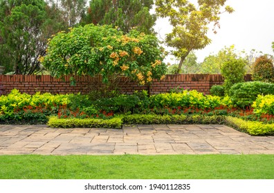 Backyard English cottage garden, colorful flowering plant and green grass lawn, brown pavement and orange brick wall, evergreen trees on background, in good care maintenance landscaping in park  - Shutterstock ID 1940112835