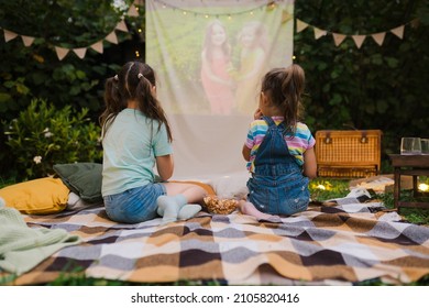 Backyard Family Outdoor Movie Night With Kids. Sisters Spending Time Together And Watching Cimema At Backyard. DIY Screen With Film. Summer Outdoor Weekend Activities With Children. Open Air Cinema.