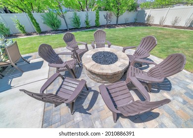 A Backyard Fire Pit Made Of Brick On The Deck Of A Home With Chairs Set Up Around It