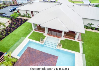 Backyard Of The House With An Attached Pool And Patio, Covered With Glass Fencing On All Sides And Divided From The Lawn Area.