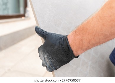  backyard improvement.Construction worker transporting a large tile slab for terrace flooring near residential building. professional tiling work. 