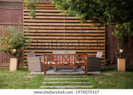 Backyard interior. Rest area. Bench with wicker chairs in the garden