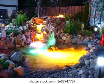 Backyard Landscaped Pond With Lights On At Night