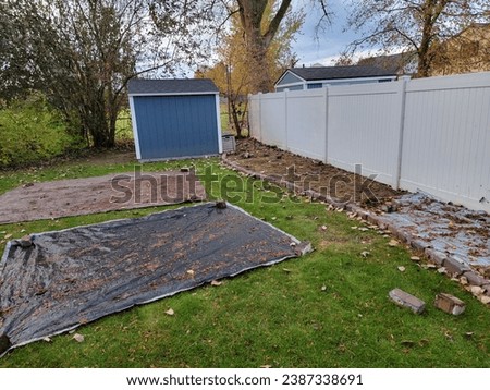 A backyard lawn smothering project in progress, with tarps pulled away to dry and dead grass in the project area