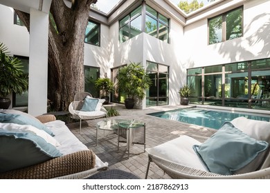 Backyard Of A Modern House With Swimming Pool, Artificial Grass, Trees, Chairs And An Umbrella.