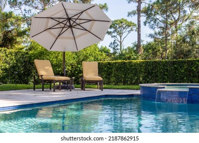 Backyard Of A Modern House With Swimming Pool, Artificial Grass, Trees, Chairs And An Umbrella.