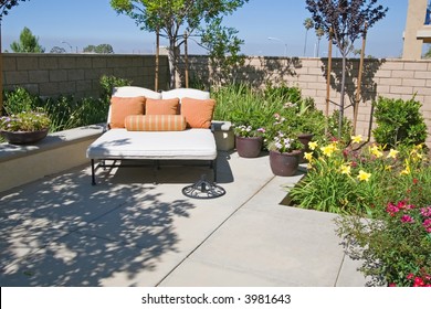 Backyard Oasis And Suburban Retreat With Flowers, Lounge Chair, And Patio