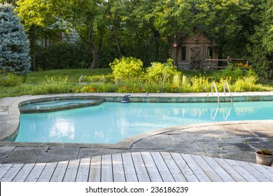 Backyard with outdoor inground residential swimming pool, garden, deck and stone patio