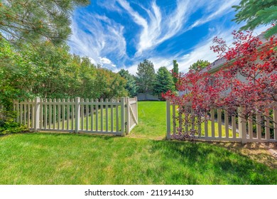 Backyard with picket fence and gate on a green lawn