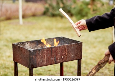 Backyard Picnic. The Man Throws Firewood Into The Brazier. Preparing For A Picnic