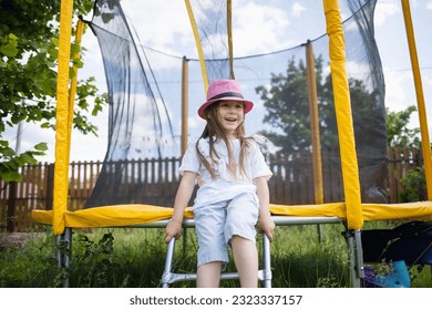 backyard playground. happy child sitting on trampoline in summer outdoor. Kids fun - Powered by Shutterstock