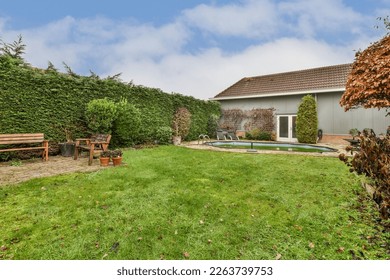 a backyard with a pool in the middle and some trees on the other side of the yard to the right