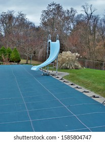 Backyard Swimming Pool With Diving Board And Pool Slide Tarped Up And Closed Down For Winter