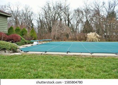 Backyard Swimming Pool With Diving Board And Pool Slide Tarped Up And Closed Down For Winter