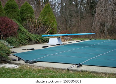 Backyard Swimming Pool With Diving Board And Pool Slide Tarped Up And Closed Down For Winter