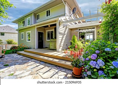 Backyard With Tile Floor And Wooden Walkout Deck. Beautiful Blooming Flowers