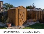 A backyard tool shed with a wooden fence.