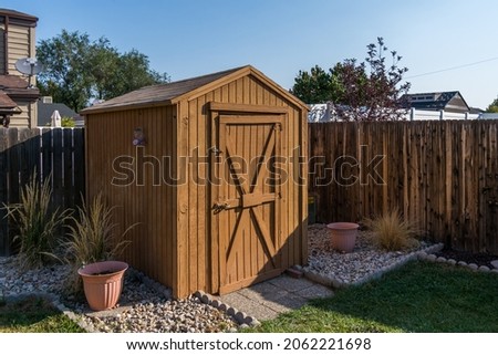 A backyard tool shed with a wooden fence.