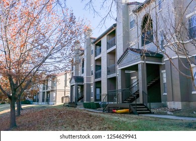 Backyard view of apartment complex at the end of fall season with thick carpet of ground dried leaves. Rental units near Dallas, Texas, USA