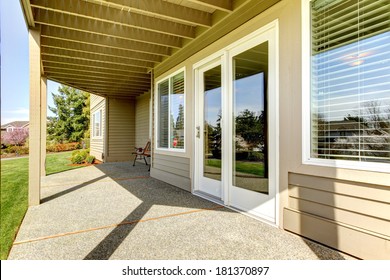 Backyard walkout deck with concrete floor. View of slide doors and windows