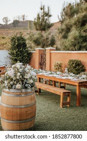 Backyard Wedding Setting - Wooden Tables With Bohemian Decor Around Swimming Pool.