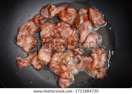 Bacon being fried in the frying pan - Stock photo