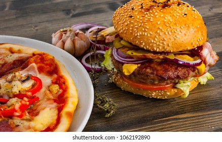 Bacon Cheese Burger With Beef Patty Tomato Onion And Pizza On A Wooden Table