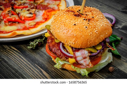 Bacon Cheese Burger With Beef Patty Tomato Onion And Pizza On A Wooden Table