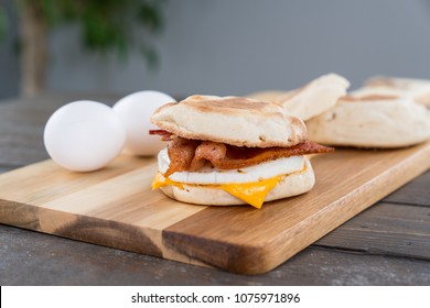 Bacon, Egg And Cheese Breakfast Sandwich With English Muffin On Cutting Board