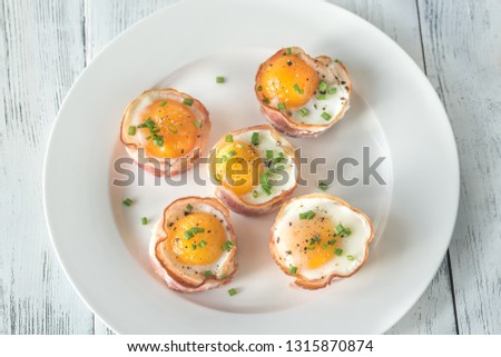 Bacon and egg cups on the white plate: top view