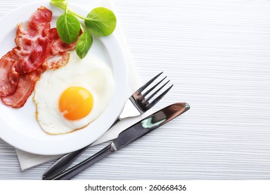 Bacon And Eggs On Color Wooden Table Background