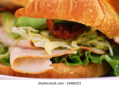 Bacon, Lettuce, Tomato, Turkey And Avocado Sandwich On A Croissant At An Outdoor Cafe