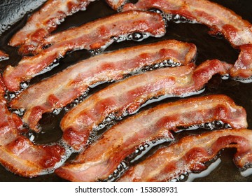 Bacon Strips Or Rashers Being Cooked In Frying Pan.