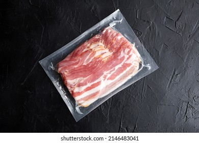 Bacon Strips, Raw Smoked Pork Meat Slices In Vacuum Package On Black Stone Table Top View