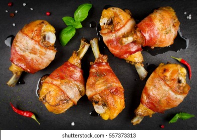 Bacon wrapped chicken legs on a black background. Top view