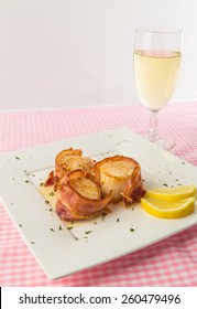 Bacon-wrapped Sauteed Scallops With Stemmed Glass Of Mosel Riesling White Wine On Pink Gingham Tablecloth.