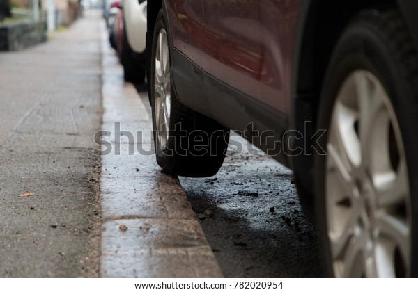 Bad car parking with part of the rear tyre on\
the pavement