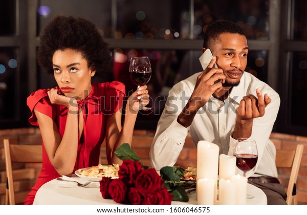 Bad Date. Bored\
African American Girl Waiting While Boyfriend Talking On Phone\
Having Dinner In\
Restaurant.