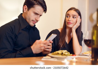 Bad Date. Unhappy Sad Beautiful Woman Is Getting Bored Sitting On Date Event In Restaurant While Her Boyfriend Using Mobile Phone And Chatting, Ignoring His Girlfriend. Relationship Problem Concept