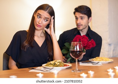 Bad Date. Young Couple Having Unsuccessful Meeting In Restaurant, Funny Disappointed Shoked Woman Feeling Embarrassment Covering Face, Man Giving Her Bouquet Of Red Roses