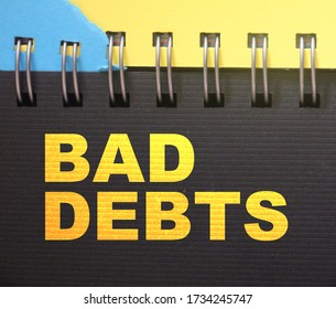 Bad debts words on page of copybook in yellow on black. Measuring size of debt refinancing business financial concept.