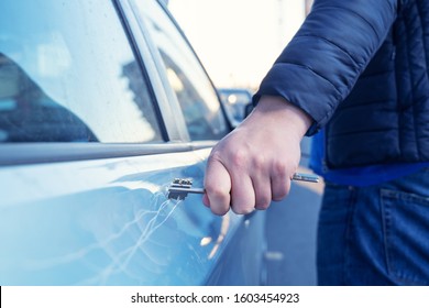 Bad guy scratching the car door with a key in the parking lot on the street. Damage of property from revenge for treason or betrayal, or threat. Auto insurance fraud or vandalism. 