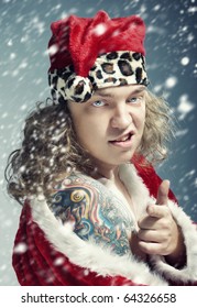 Bad Man With Colored Tattoo In The Red Santa Claus Costume Under The Heavy Snowstorm