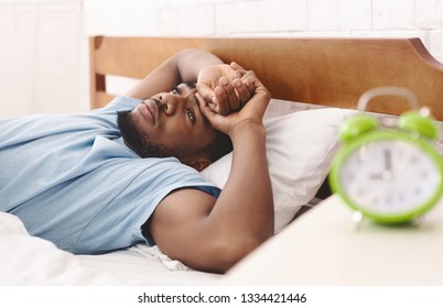 Bad mood in morning. Overslept black guy lying in bed and conteplaining, closeup