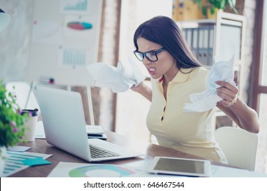 Bad Mood. Young Angry Businesswoman Is Casual Clothes And Glasses Is Tired From Work In The Office, Crumpling Papers And Yelling At The Laptop