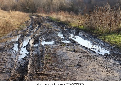 Bad muddy dirt сountry road after the rain puddles and car track. 

