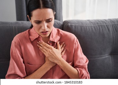 Bad news. Stressed young woman feeling pain and touching chest suffer from heartache disease at home while having heart attack, infarction